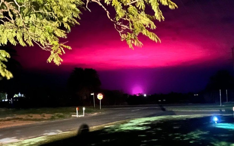 Cannabisfarmens odlingslampor gör himlen över en liten australisk stad ljusrosa